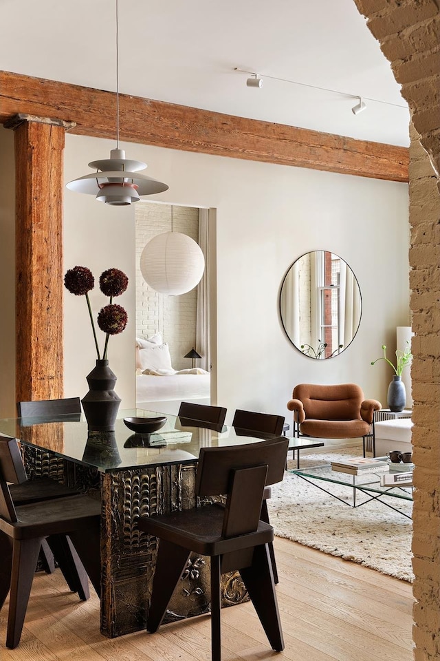 dining space with beamed ceiling and wood finished floors