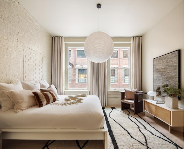 bedroom featuring multiple windows and brick wall