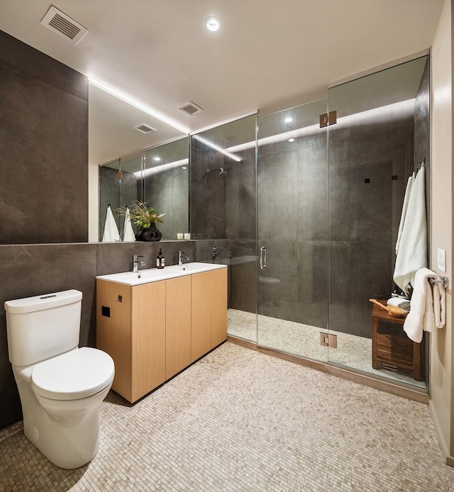 bathroom with a stall shower, visible vents, double vanity, and toilet