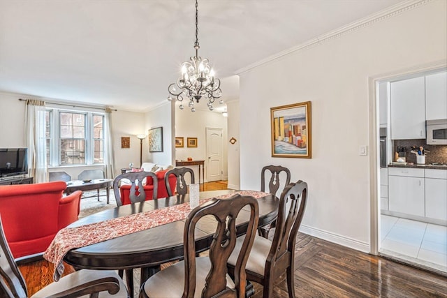 dining area with dark wood finished floors, crown molding, a notable chandelier, and baseboards