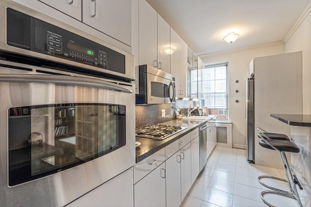 kitchen featuring dark countertops, decorative backsplash, stainless steel appliances, and ornamental molding