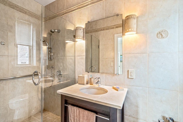 full bath with vanity, a shower stall, toilet, and tile walls