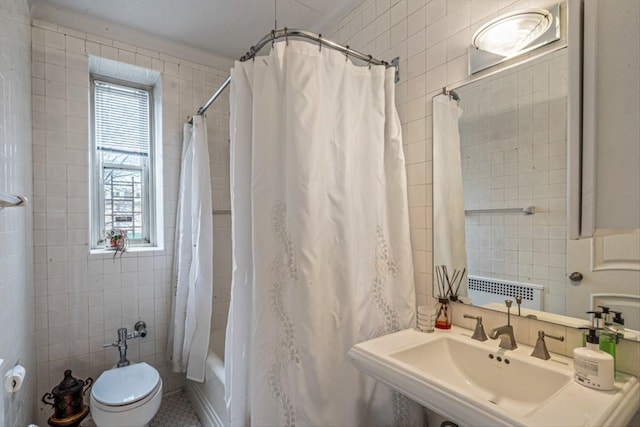 bathroom featuring radiator, a sink, tile walls, toilet, and shower / tub combo with curtain