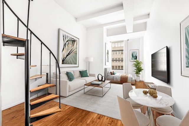 living room featuring beam ceiling, stairway, baseboards, and wood finished floors