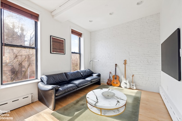 living room with a baseboard heating unit, wood finished floors, baseboard heating, and brick wall