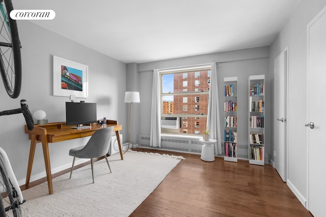 office area featuring visible vents, baseboards, wood finished floors, and radiator heating unit