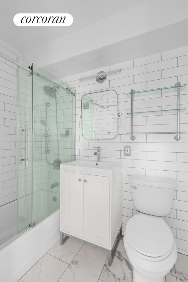 bathroom with vanity, shower / bath combination with glass door, tile walls, toilet, and marble finish floor