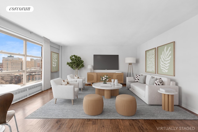 living room with a city view, radiator heating unit, wood finished floors, and visible vents