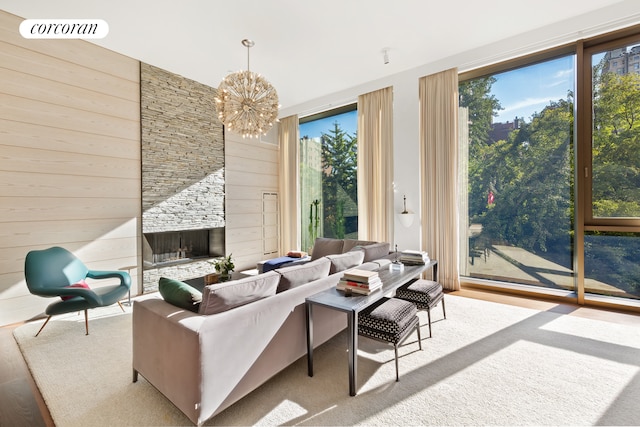 living area featuring visible vents, a stone fireplace, a chandelier, and wood walls