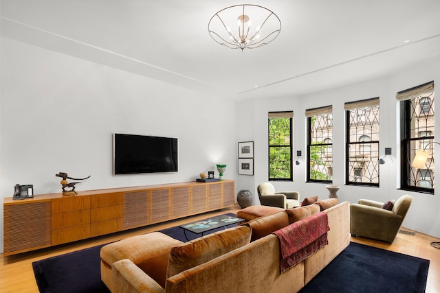 living area with wood finished floors, visible vents, and a chandelier