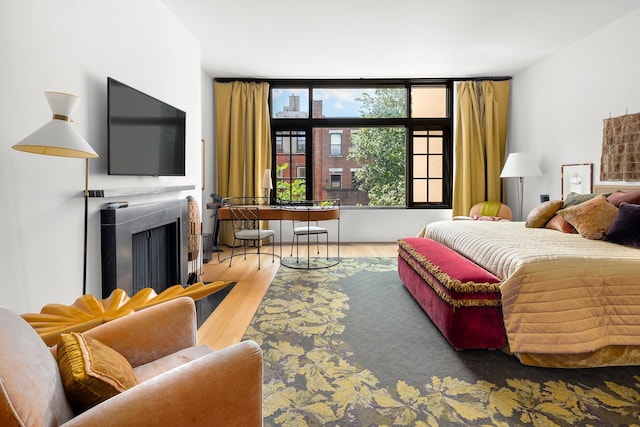 bedroom with a fireplace with flush hearth and wood finished floors