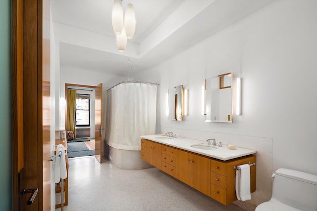 full bathroom featuring toilet, a shower with shower curtain, a raised ceiling, and a sink