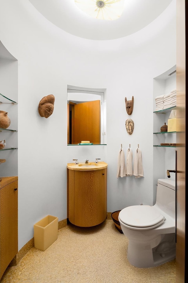 bathroom featuring toilet, vanity, and baseboards