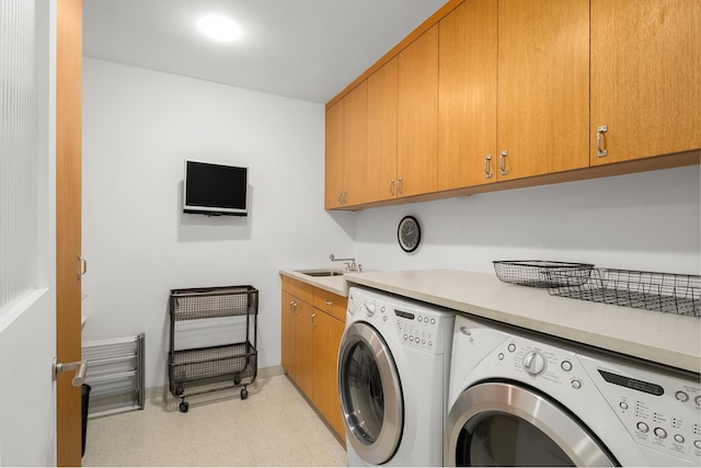 clothes washing area with cabinet space, washer and dryer, light floors, and a sink