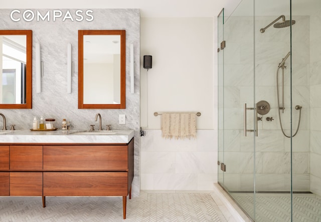 bathroom with a shower stall, double vanity, and a sink