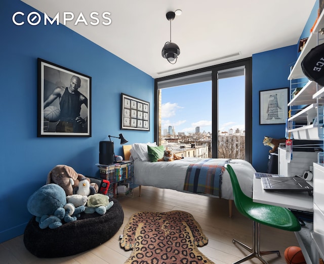 bedroom featuring a view of city and wood finished floors