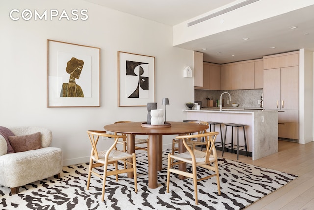 dining space with light wood-style flooring, recessed lighting, and baseboards