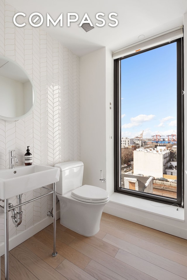 half bathroom featuring toilet, wood finished floors, and visible vents