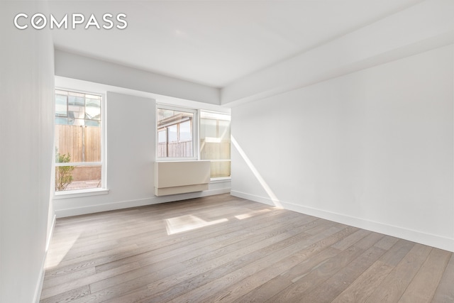 unfurnished room with baseboards and wood-type flooring