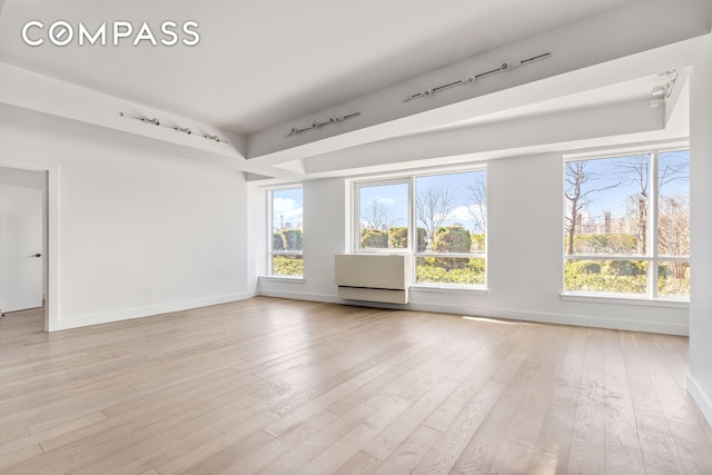 unfurnished room featuring light wood-style floors, baseboards, and rail lighting