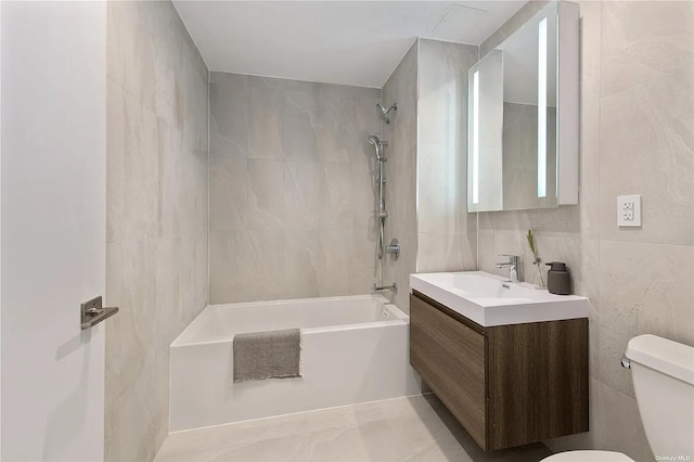 bathroom featuring tub / shower combination, toilet, tile walls, and vanity