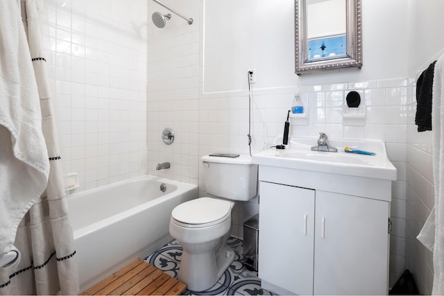 full bathroom featuring tile walls, toilet, shower / tub combo with curtain, wainscoting, and vanity