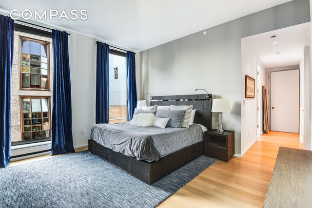 505 W 19th St Unit 7W, New York City, NY 10011 - bedroom with baseboards, wood finished floors, and a baseboard heating unit