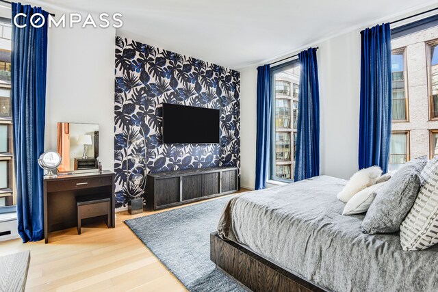 505 W 19th St Unit 7W, New York City, NY 10011 - bedroom featuring wallpapered walls, wood finished floors, and an accent wall