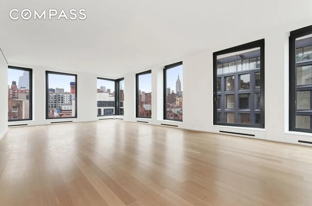 505 W 19th St Unit 7W, New York City, NY 10011 - unfurnished living room featuring wood finished floors and a city view