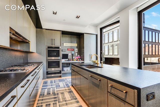 kitchen featuring a sink, stainless steel appliances, tasteful backsplash, and a wealth of natural light