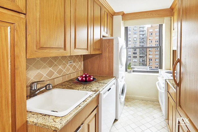 clothes washing area with a sink, light tile patterned floors, and stacked washer / dryer