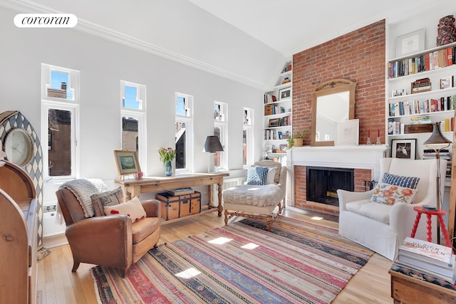 living room featuring visible vents, built in shelves, ornamental molding, wood finished floors, and a fireplace