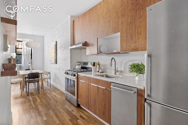 kitchen featuring modern cabinets, a sink, open shelves, under cabinet range hood, and appliances with stainless steel finishes