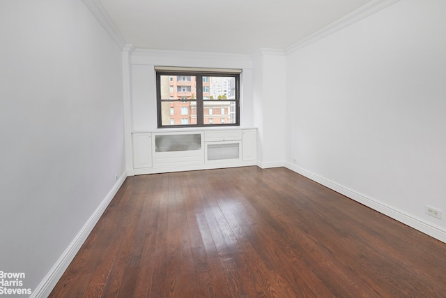 empty room featuring dark wood-style floors, baseboards, and ornamental molding