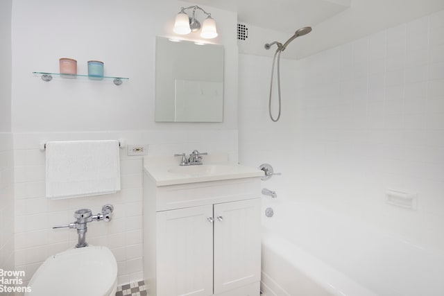 full bath with vanity, a wainscoted wall, shower / tub combination, tile walls, and toilet