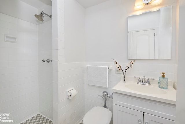 full bathroom with a wainscoted wall, toilet, a tile shower, tile walls, and vanity