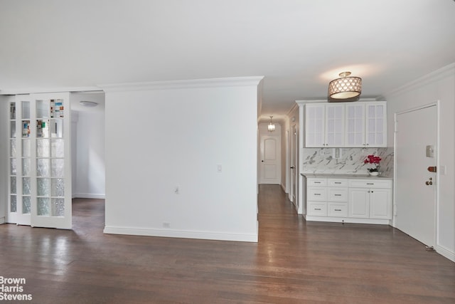 interior space featuring dark wood finished floors, baseboards, and ornamental molding