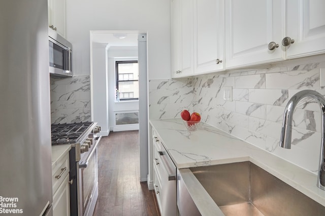 176 E 77th St Unit 7D, New York City, NY 10075 - kitchen featuring appliances with stainless steel finishes, a sink, light stone countertops, white cabinetry, and backsplash