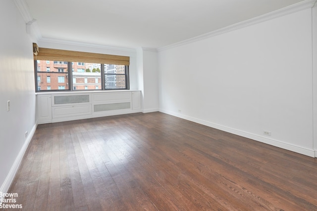 spare room with crown molding, baseboards, and dark wood-style flooring