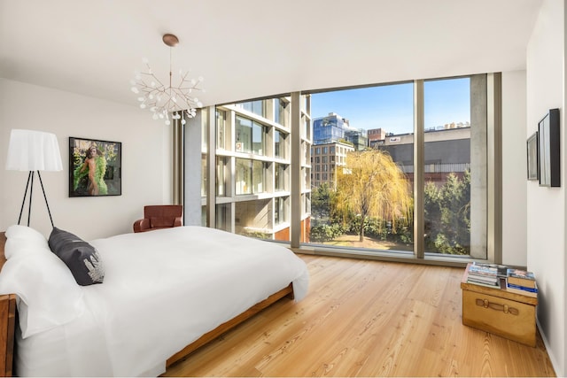 bedroom featuring a wall of windows, an inviting chandelier, and wood finished floors