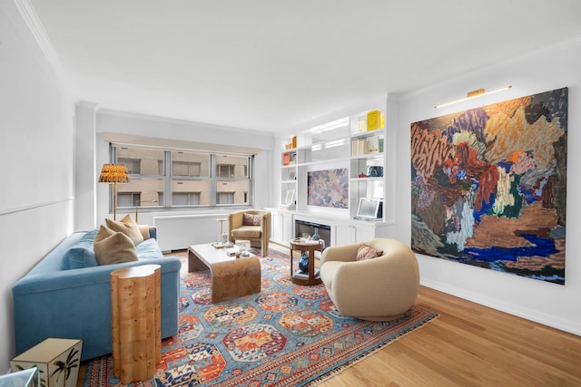 living room with wood finished floors, baseboards, and ornamental molding