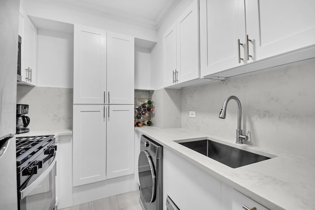 kitchen with a sink, light stone counters, washer / clothes dryer, gas range oven, and white cabinets