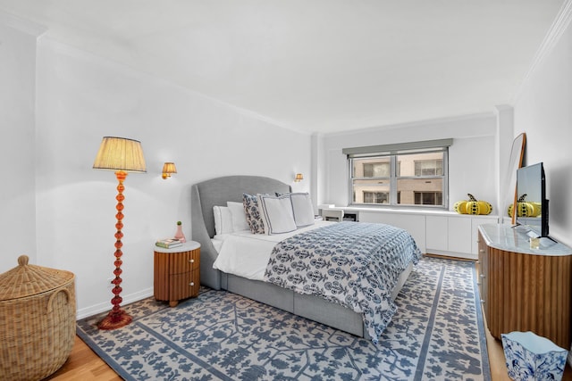 bedroom with baseboards, crown molding, and light wood-style floors