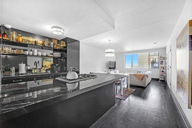 kitchen with open floor plan, hanging light fixtures, stainless steel gas stovetop, dark wood-style floors, and open shelves