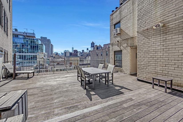 wooden deck featuring a city view, outdoor dining area, and cooling unit