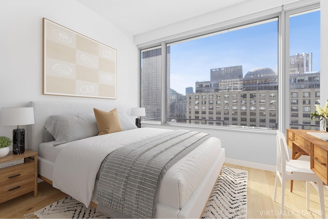 bedroom with a view of city and wood finished floors