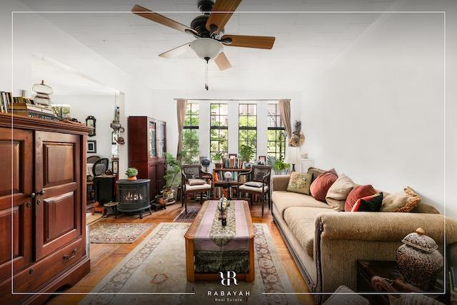 living room featuring a wood stove, wood finished floors, and ceiling fan