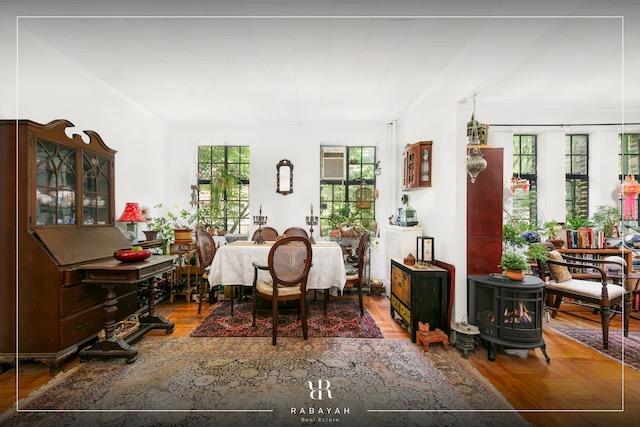 dining space with a wealth of natural light, wood finished floors, and a wood stove