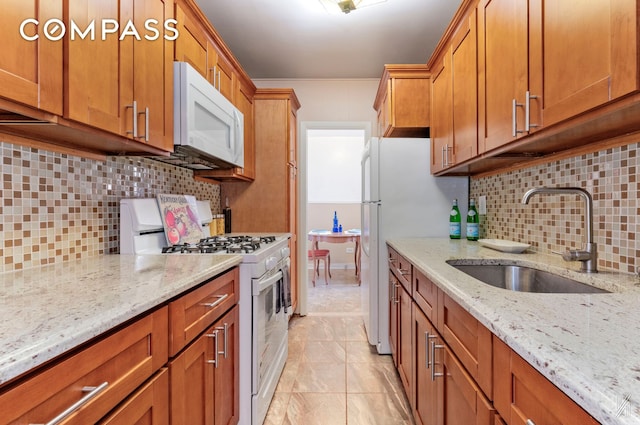 kitchen with a sink, brown cabinetry, backsplash, and white appliances