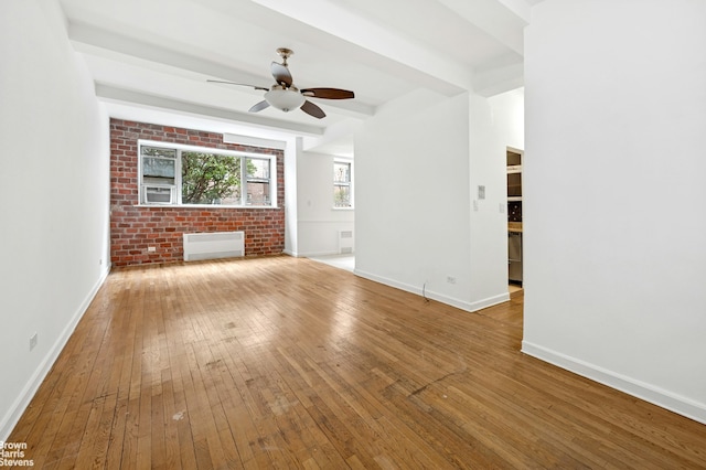 unfurnished living room with beam ceiling, hardwood / wood-style flooring, radiator, baseboards, and ceiling fan